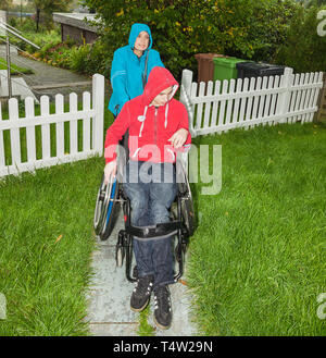 Mutter mit behinderten Sohn im Regen Stockfoto