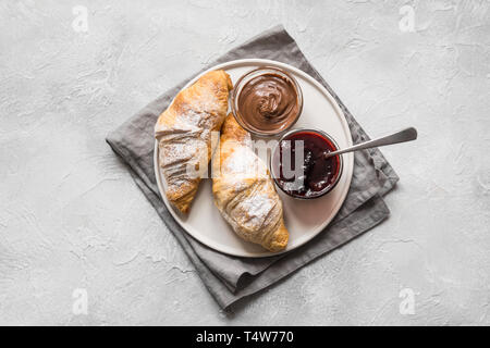 Frisch gebackene Croissants mit Berry jam auf grauem Hintergrund. Ansicht von oben. Stockfoto