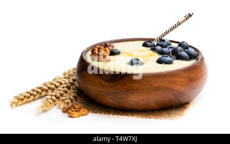 Hölzerne Schüssel von Grieß Brei mit Heidelbeeren und Nussbaum isoliert auf weißem Stockfoto