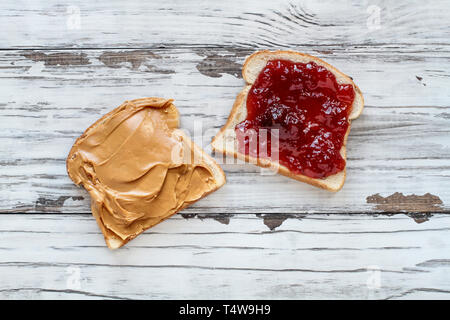 Ansicht von oben offenem Gesicht selbstgemachte Erdnussbutter und Strawberry Jelly Sandwich auf Hafer Brot, über einem weißen rustikalen Holztisch/Hintergrund. Stockfoto