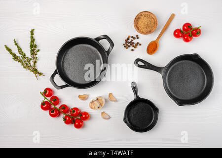 Gusseisen skillets und Gewürzen auf weißen Holzmöbeln kulinarischen Hintergrund, Ansicht von oben Stockfoto