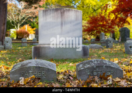 Grabsteine inmitten des grünen Grases und gefallene Laub auf einer sonnigen Herbst Tag in Upstate New York, NY, USA Stockfoto