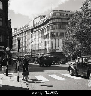1960, historische, zwei Damen, die man über einen Bahnübergang am Sloane Square, Chelsea, London, mit der großen Glasfront Department Store, Peter Jones, gegründet im Jahr 1877, auf der Kings Road, in der Ferne zu sehen. Stockfoto