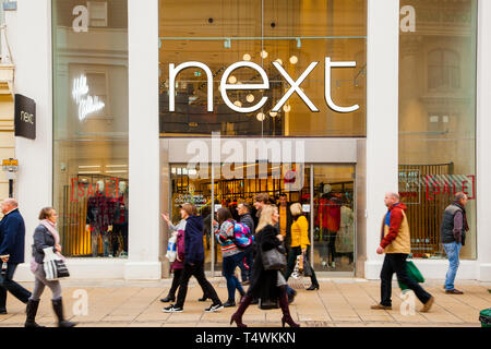 Käufer wandern vorbei an der High Street Fashion kleidung shop Händler weiter in der Stadt Cheltenham Gloucestershire England Großbritannien Stockfoto