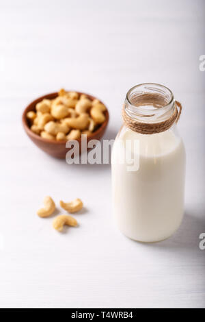 Gesunde natürliche nicht Molkerei Milch in der Flasche und Schüssel von Cashew-nüssen auf weißen Tisch Stockfoto