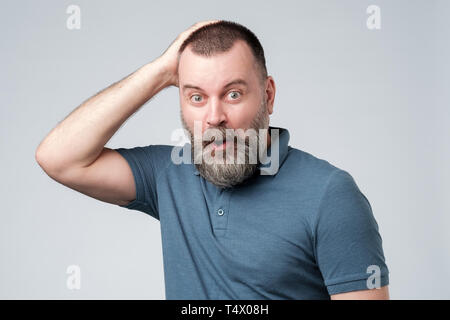 Reifer Mann im blauen T-Shirt sieht mit erschrockenen Ausdruck wie sieht etwas schrecklich vor Stockfoto