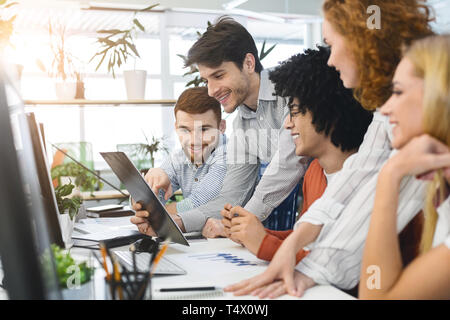 Junge fröhliche Menschen auf Zwischenablage an coworking Arbeitsplatz Stockfoto