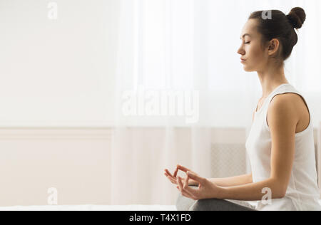 Ruhe bewahren. Junge Frau im Lotossitz zu Hause sitzen Stockfoto