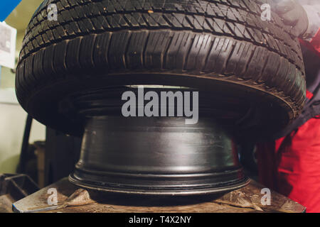 Handwerker gleicht die Rad- und installiert den schlauchlosen Reifen des Autos auf der Radauswuchtmaschine in der Werkstatt Stockfoto