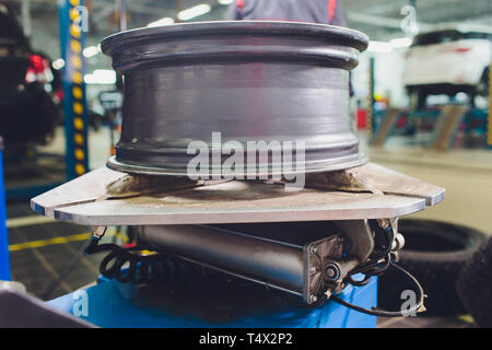 Handwerker gleicht die Rad- und installiert den schlauchlosen Reifen des Autos auf der Radauswuchtmaschine in der Werkstatt Stockfoto