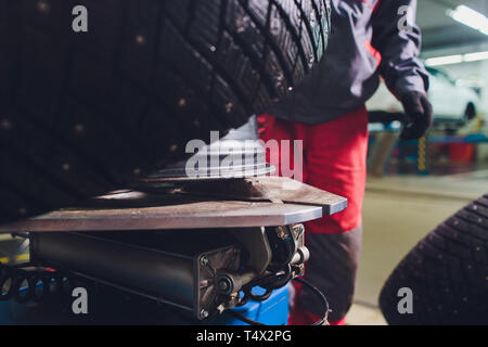 Handwerker gleicht die Rad- und installiert den schlauchlosen Reifen des Autos auf der Radauswuchtmaschine in der Werkstatt Stockfoto