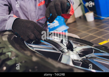 Handwerker gleicht die Rad- und installiert den schlauchlosen Reifen des Autos auf der Radauswuchtmaschine in der Werkstatt Stockfoto