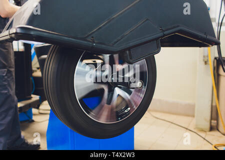 Handwerker gleicht die Rad- und installiert den schlauchlosen Reifen des Autos auf der Radauswuchtmaschine in der Werkstatt Stockfoto