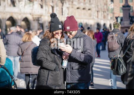 München, Deutschland. 17. Februar 2019. Schöne junge glückliches Paar an Smartphone Display im Zentrum der Stadt suchen Stockfoto