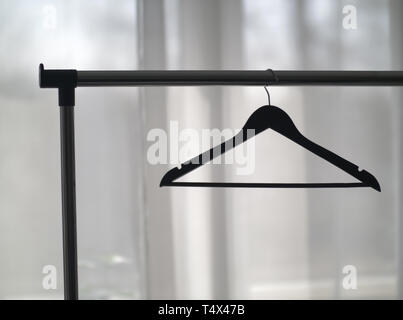 Kleiderbügel auf einer Metallschiene gegen das Fenster Stockfoto