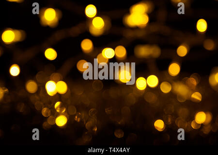 Abstrakte gold Bokeh auf schwarzem Hintergrund. Defokussierten gelb leuchten, abstrakte Textur. Stockfoto