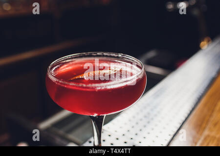 Cocktail Glas mit Drink in der Bar mit Flaschen in den dunklen Hintergrund. Stockfoto