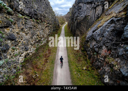 Ein Mann fährt mit dem Fahrrad durch einen Schnitt entlang der Monsal Trail in The Derbyshire Peak District. Stockfoto