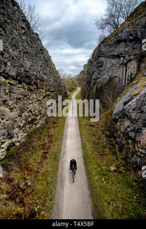 Ein Mann fährt mit dem Fahrrad durch einen Schnitt entlang der Monsal Trail in The Derbyshire Peak District. Stockfoto