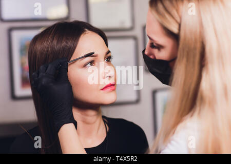 Kosmetiker die Augenbrauen Design. Attraktive Frau, Gesichtspflege im Beauty Salon. Perfekte Architektur Augenbrauen. Stockfoto