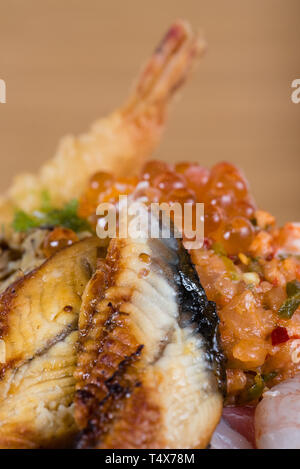 Typische japanische Fisch donburi, Shrimp Tempura, rohe Garnelen, Lachs Filets, gegrillter Thunfisch, Kaviar, Thunfisch Tartar, in Scheiben geschnittene Gurken, raw Wolfsbarsch Fischfilets Stockfoto
