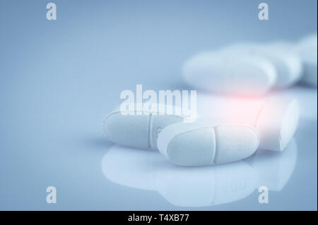 Stapel der Weiße Oblong-Tabletten Pillen auf farbverlauf Hintergrund. Pharmazeutische Industrie. Apotheke Produkt. Global Healthcare. Droge in der Apotheke, Drogerie oder Stockfoto
