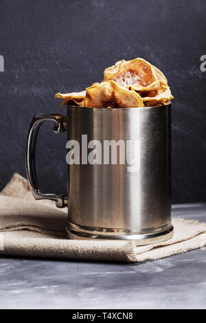 Metall Becher mit Apple Chips stehen auf sackleinen auf dunklem Hintergrund. Stockfoto