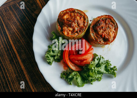 Runde Zucchini gefüllt mit Gemüse und Reis auf weiße Platte Stockfoto