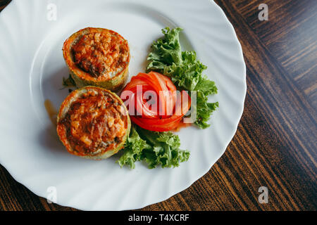 Runde Zucchini gefüllt mit Gemüse und Reis auf weiße Platte Stockfoto