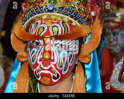 Junge taiwanesische Tänzer trägt traditionelle Taoistische Krieger Gesicht Farbe, eine prächtige Kopfbedeckungen und dramatische fake Augenbrauen. Stockfoto