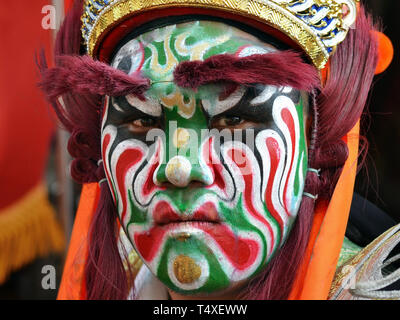 Junge taiwanesische Mann (Street Performer eines zhentou Truppe während einer taoistischen Tempel Parade) hat sein Gesicht mit einem dramatischen Peking Oper Maske gemalt. Stockfoto