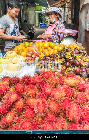 Bangkok, Thailand - 31. Januar 2019: Früchte Anbieter mit Kunden in einer Gasse in Chinatown. Obst ist ein beliebter Snack. Stockfoto