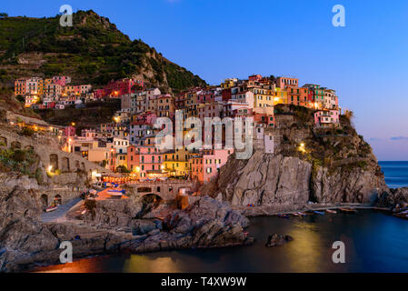 Sonnenuntergang und Nacht Blick über Manarola, einer der fünf mediterranen Dörfer der Cinque Terre, Italien, bekannt für seine bunten Häuser und den Hafen. Stockfoto