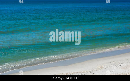 Ein eng beschnitten seascape Blick auf meistens blaue und türkisfarbene Wasser mit sehr milden surf Startpositionen zu einem weißen Sandstrand im Südwesten Florida, USA Stockfoto