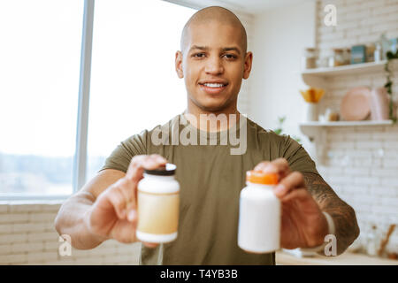 Dark-eyed Mann mit zwei Paketen von Nahrungsergänzungen für Bodybuilder Stockfoto