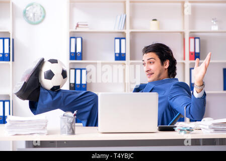 Junge gut aussehender Geschäftsmann mit Fußball im Büro Stockfoto