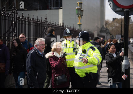 London, Großbritannien, 13. April 2019: - Zwei Polizisten Leuten helfen außerhalb Westminster Parlament des Vereinigten Königreichs Stockfoto