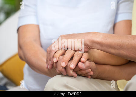 Close up Asiatische senior Paar zusammen, indem sie einander die Hand auf einem Sofa im Wohnzimmer zu Hause ermutigend. glücklichen Ruhestand Lifestyle. Altern zu Hause Stockfoto