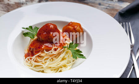 Nahaufnahme Spaghetti mit Fleischbällchen in Tomatensauce auf einem weißen Teller Stockfoto