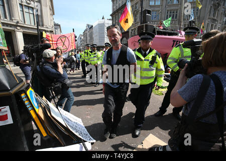 Ein Aussterben Rebellion Demonstrator wird weg von der Polizei geführt, wie Proteste in Oxford Circus, London fort. Stockfoto