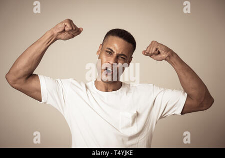 Junge starke stattliche afrikanische amerikanische Mann, die Arme Muskeln lächelt Stolz, Spaß haben. In Menschen, Glück, Fitness, Erfolg, die menschliche Emotionen und Fa Stockfoto