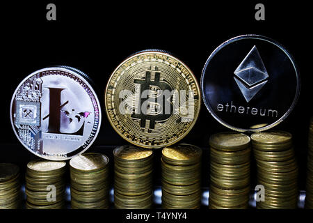 Physische Litecoin LTC, Bitcoin BTC und des Astraleums ETH auf einem dunklen Hintergrund und Goldmünzen. Konzept der cryptocurrency. Stockfoto