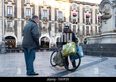 Sizilien, Italien - Januar 21, 2016: Mann Tragetaschen mit seinem Fahrrad heute morgen am Piazzo Duomo im Zentrum von Catania. Stockfoto