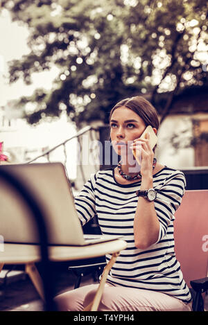 Ernsthafte junge Frau ein Handy an ihr Ohr Stockfoto