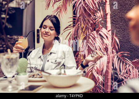 Freudige schwarzhaarige Frau mit einem Cocktail Stockfoto