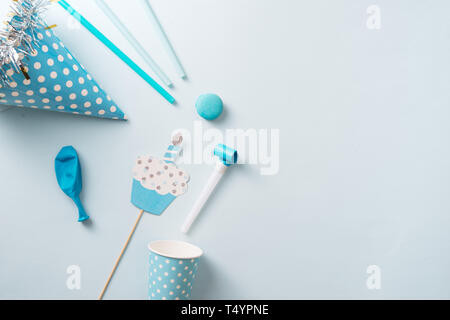 Junge geburtstag Dekorationen. Blauer Tisch Einstellung von oben mit Muffins, Drinks und Party Gadgets. Hintergrund Layout mit Freier Text. Stockfoto