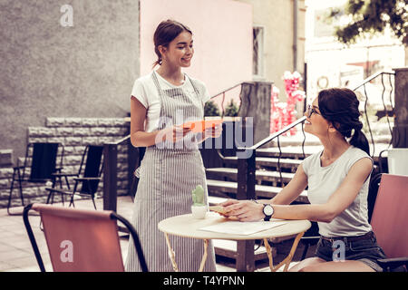 Freudige freundliche Kellnerin die Bestellung von Ihren Kunden Stockfoto