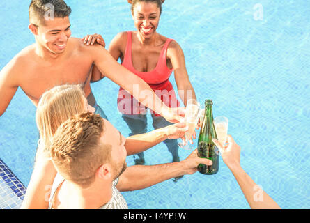 Gerne Freunde jubeln mit Champagner in den Pool - den Jugendlichen Spaß macht eine Partei und toasten Gläser Prosecco Stockfoto