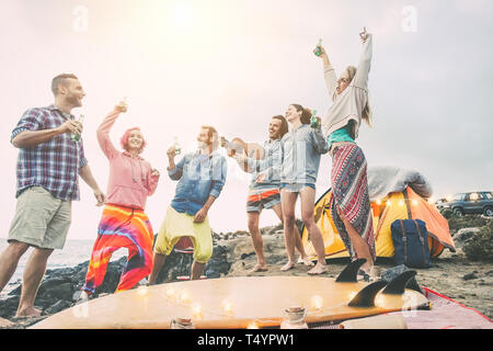 Gerne Freunde tanzen und Spaß haben, eine Beach Party auf dem Campingplatz - Junge Menschen lachen und trinken Bier beim Camping nächsten Ozean Stockfoto