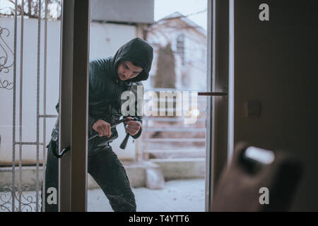 Raub Kerl mit der Brechstange versucht, Tür von Haus zu öffnen. Stockfoto